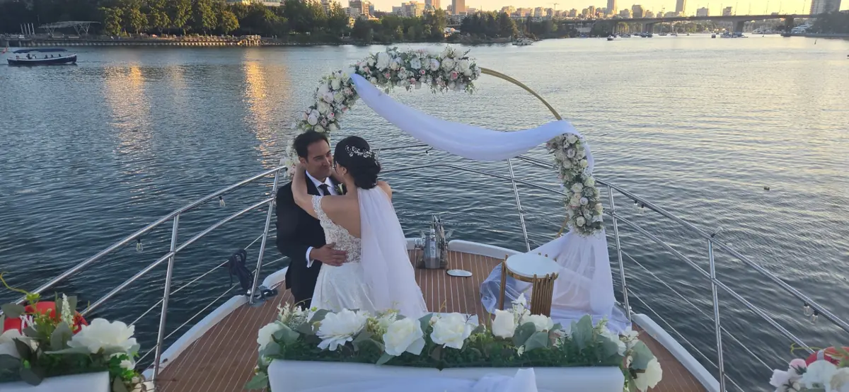 Bride and groom on Joy's bow with floral arch and skyline