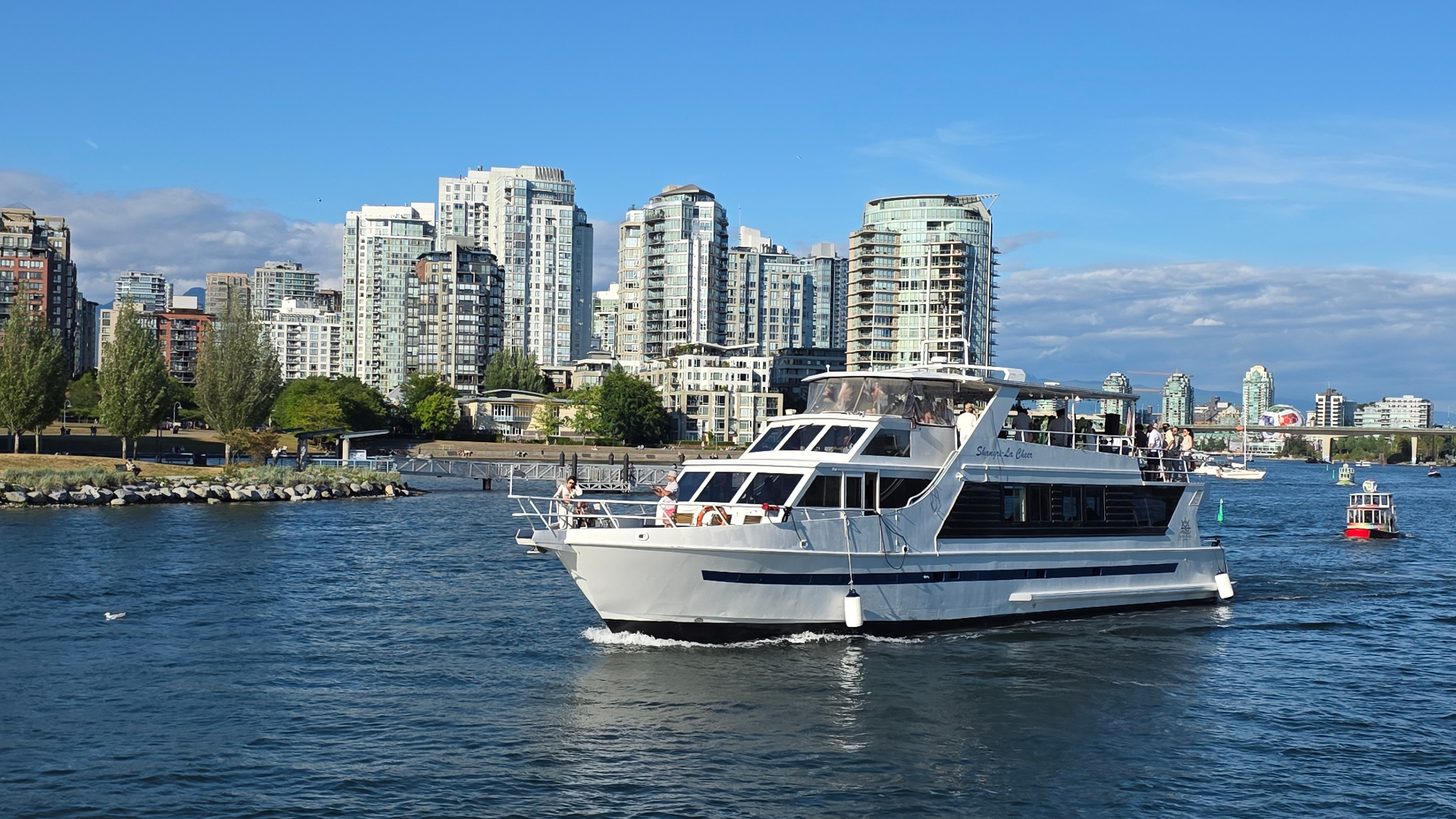 Guests enjoying a private yacht event at sunset with the Vancouver skyline in the distance